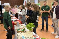 Personen stehen um einen langen Tisch mit verschiedenen Gegenständen
