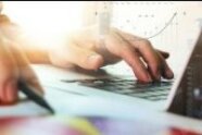 Zwei Hände am Laptop und an einem Kugelschreiber
