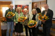 Personen stehen im Halbkreis mit Blumensträuße zusammen