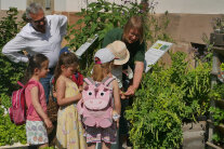Erwachsene und Kinder stehen neben einem Beet